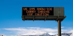 Image of electronic road sign, warning motorists of ice and snow conditions ahead.